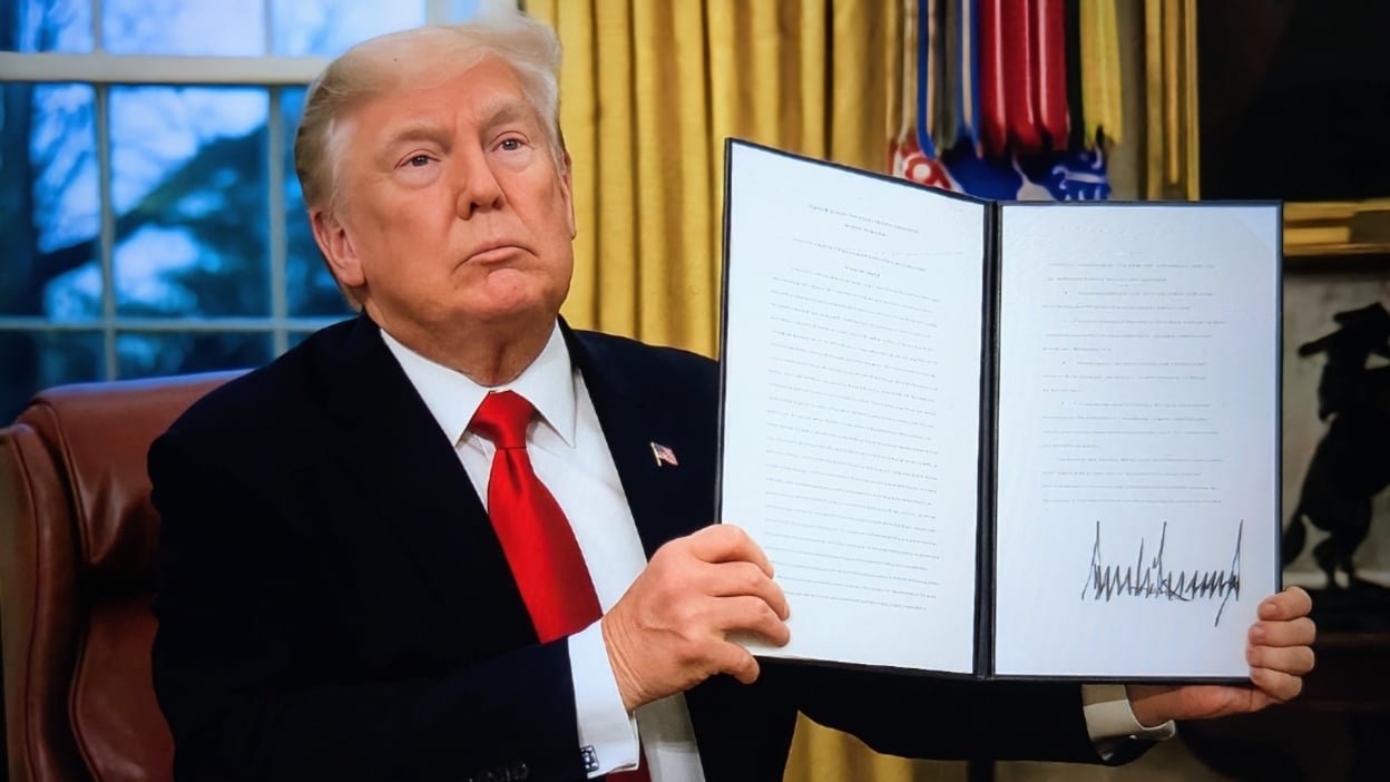 President Donald Trump holds up an executive order in the oval office