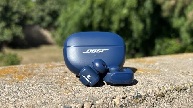 blue bose ultra open earbuds on wall in front of greenery